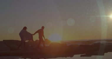 Tutuşan ve kayalık kıyı şeridine ayak basan çift, günbatımının parıltısını ve turizm için lensleri yakıyor. Romantik, macera, alacakaranlık, manzara, yansıma, ufuk, sükunet