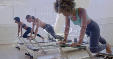 Spor kıyafetleri giyen üç kadın stüdyoda spor saatleriyle pilates yenilikçilerine tahta tutuyorlar. Zindelik, sağlık, egzersiz, güç, denge, aktif giysi, sağlık