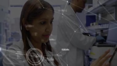 Laboratuar bilim adamı tableti tıklatıyor, takım tüpler yüklerken ağı kuruyor, analiz için verileri takip ediyor. Araştırma, yenilik, bağlantı, teknoloji, işbirliği, analitik, moleküler