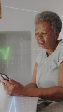 Akıllı telefon kullanan yaşlı Afro-Amerikan bir kadının kardiyografisinin animasyonu. Küresel sağlık, tıp, yaşam tarzı ve dijital arayüz kavramı dijital olarak oluşturulmuş video.