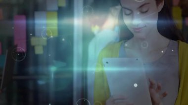 Kadın tableti tıklayarak bilişim ağını başlatıyor. İş arkadaşı olarak cihaza bağlanıyor. Yapışkan notlar ekliyor. Teknoloji, yenilik, işbirliği, dijital, modern, çalışma alanı, bağlantı