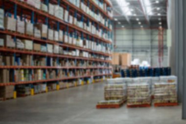 Aydınlatılmış depoda raflara dizilmiş karton kutular.