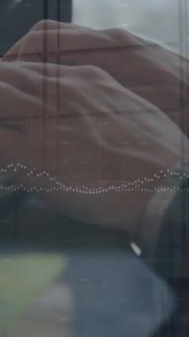 The hands of a young caucasian male business creative are shown typing on a computer keyboard and mouse. This is a business and technology concept video that combines statistical data processing with a time lapse of people walking in an office.