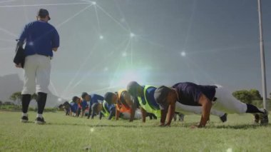 Koç, beysbol oyuncularının yanında yürüyor ve güç kazanmak için şınav çekmeye başlıyor. Atletizm, takım çalışması, açık hava, fitness, kararlılık, eğitim, hareket