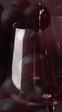 Kırmızı arka planda üzümlerin üzerine kırmızı şarap dökülüyor. Şarap, içki, içki ve alkol konsepti.