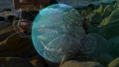Kayalık günbatımı sahili üzerinde meditasyon yapan bir kadın hologram küresi ve kaydırmalı veri üretiyor. Gelecek, dinginlik, dijital, manzara, yenilik, sükunet, minimalizm