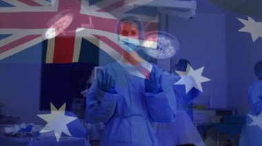 Cerrahi ekip ameliyata hazırlanırken Avustralya bayrağı ışıkları ve enstrümanlar üzerinde kayboluyor. Tıbbi, takım çalışması, steril, klinik, hassasiyet, esneklik, profesyonel