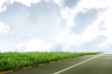 Çimenlerin bulutlu gökyüzüne karşı dosyaladığı boş yol manzarası