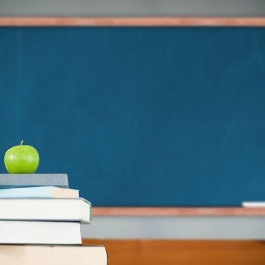 Sınıfta kitap yığınının üzerinde yeşil elma