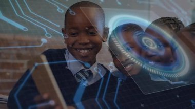 Öğrenciler tablet kaldıran çocuğa yaslanıyor ve öğrenme arayüzünde mavi devre ekranını başlatıyorlar. Dijital, yenilik, işbirliği, teknoloji, eğitim, fütüristik, gençlik