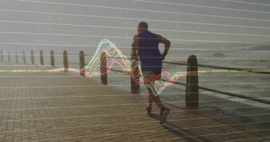 Son sınıf erkek koşucu deniz kenarındaki patikaya giriyor ve koşuyor. Bu sırada spor izleme için nabız atıyor. Fitness, sağlık, azim, zindelik, açık hava, manzara, modern