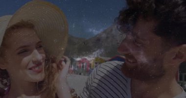 Hasır şapkalı çift plajda durup merceklerin parlamasını seyrediyor ve seyahat için yıldız alanı örtüsünü ortaya çıkarıyor. Sahil, açık hava, hareketli, manzaralı, romantik, neşeli