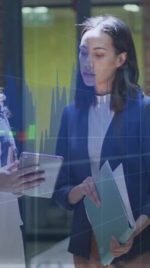 Animation of financial data processing over diverse businesswomen in office. Global business, finances, computing and data processing concept digitally generated video.