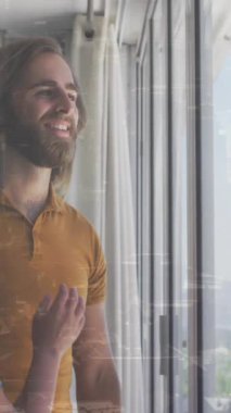 Evdeki geniş pencereden dışarı bakan birbirine sarılan çift ekranda canlandırma yapıyor. İlişki, teknoloji, ev hayatı, kapalı alan, rahatlama, bağlanma