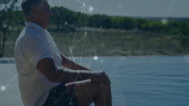 Kamera, havuz başındaki adamı görüntülüyor. Teknoloji tanıtımı için ağ örtüsüyle etkileşimde. Teknoloji, bağlantı, eğlence, açık hava, rahatlama, modern, yenilik