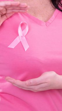 Beyaz kadın, pembe arka planda pembe kanser farkındalığı kurdelesi takıyor. Göğüs kanseri pozitif farkındalık kampanyası konsepti.