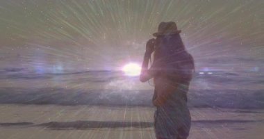 Kadın fotoğrafçı güneşi çerçeveliyor, gün batımını yakalıyor ve okyanus boyunca yıldız patlaması ışınları üretiyor. Meditasyon, huzur, ilham, sükunet, doğa, macera, açık hava