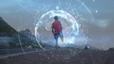Sahil yolunda duran koşucu, teknoloji küresi titreşim verileriyle ısınma hareketleri yapıyor. Fitness, teknoloji, yenilik, açık hava, canlılık, spor, sağlık
