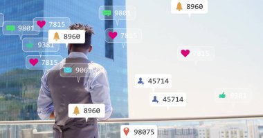 Balkonda duran adam, sosyal medya tebligatları ile şehir manzarası üzerinde duruyor. Teknoloji, iletişim, dijital ağ, yaşam tarzı, gökdelen