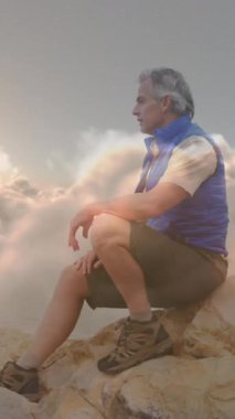 Hızlı hareket eden bulutların üzerinde dağlarda yürüyüş yapan Kafkasyalı kıdemli mutlu adam. etkin emeklilik yaşam tarzı konsepti dijital olarak oluşturulmuş video.