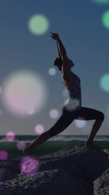 Kumsalda yoga yapan beyaz bir kadının üzerine ışık animasyonu. Etkin yaşam tarzı, spor, rahatlama ve deniz konsepti dijital olarak oluşturulmuş video.