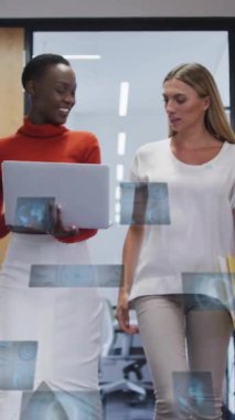 Dijital veri animasyonlarıyla ofiste yürüyen iki kadın. İş, teknoloji, yenilik, takım çalışması, analitik, işbirliği