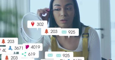 Güzellik yaratıcısı maskara sürüyor ve aynanın etrafında yüzen sosyal ikonlar yaratarak büyümeyi kutluyor. Kozmetik, etkili, dijital, çağdaş, yaşam tarzı, cazibe, sosyal medya