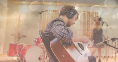 Erkek müzisyen stüdyoda gitar tıngırdatırken kadın vokalist mikrofona şarkı söylüyor. Stüdyo, caz, ambient, performans, işbirliği, akustik, kayıt