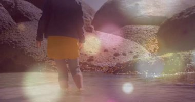 Pervazdan atlayan bir kadın, kayaların arasında dans eden mercekli turizm reklamı için gelgit havuzunu keşfediyor. Macera, keşif, sükunet, doğa, açık hava, güneş ışığı, sükunet