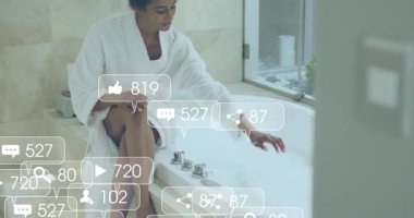 Küvette musluğa dokunan bir kadın, sosyal medya nişan ikonlarını aktif hale getiriyor. Lüks, refah, rahatlama, dijital, kişisel bakım, modern, iç mekan