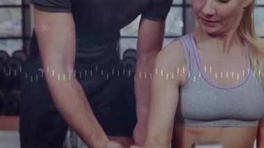 Eğitmen ellerini müşteri koluna koyuyor fitness dambıl kıvrımlarını dalga biçimi olarak geliştiriyor. Fitness, koçluk, güç, spor salonu, sağlık, danışmanlık, aktif