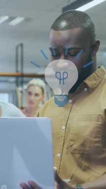 Animation of digital light bulb icons over diverse business people in office. Global business, finances, computing and data processing concept digitally generated video.