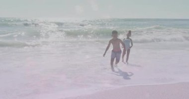 Erkek ve kız, yaklaşan ve koşan bir dalga gibi köpüklü kaplama ile kıyı şeridi sağlığını yükseltiyor. Macera, neşe, canlılık, açık hava, hareket, gençlik, neşe