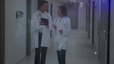 Erkek doktor tableti tıkırdatıyor. Koğuşta hayati bulguları inceleyen bir animasyon veri ağı oluşturuyor. Tıp uzmanları, işbirliği, fütüristik, teknoloji, sağlık hizmetleri, tanı, takım çalışması