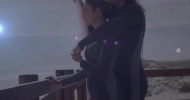 Tırabzanlara ulaştıktan sonra, iki sörfçü kum tepelerinin üzerinde yüzen animasyon dalga grafiklerine sarılıp kontrol ediyorlar. Romantik, macera, uyum, kıyı, açık hava, yaşam tarzı, dinamik