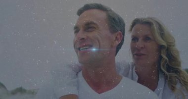 Kadın, erkeğin arkasına geçiyor ve plajda kollarını sarıyor. Teknoloji yıldızı alyansı vurguluyor. Romantizm, şefkat, bağlantı, kutlama, dinginlik, zarafet, samimiyet