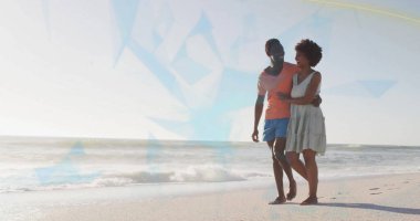 Sahilde kol kola yürüyen çift mercan gömlek, mavi şort, beyaz elbise ve fotokopi odası giyiyor. Aşk, deniz kenarı, eğlence, tatil, sükunet, canlılık, moda