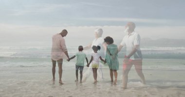 Yürüyen çok nesilli bir aile, el ele tutuşarak uzak dağlarda, sahilde sığ dalgalarda yüzüyorlar. Aile, sahil, sahil, birliktelik, kaynaşma, açık hava, manzara