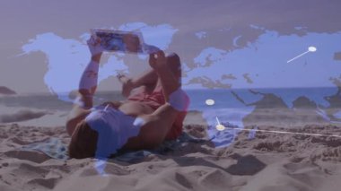 Plajdaki kadın tableti kaldırırken küresel ağ bağlantılarını gösteren dünya haritasını çıkarıyor. Teknoloji, bağlantı, dijital, açık hava, boş zaman, modern, rahatlama