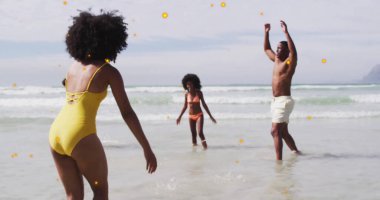 Aile fertlerini oynamak sahildeki okyanus suyunda mayo ve mayo ile oynayıp yakalamak. Deniz manzarası, boş zaman, neşeli, canlı, açık hava, güneş, mutluluk.