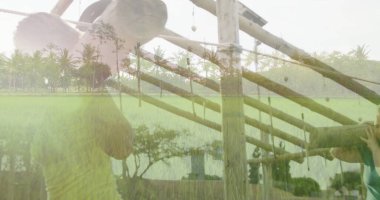 Asyalı bir adam, pirinç bitkileri ve palmiye ağaçları olan, taşra köşkünde ahşap kiriş taşıyor. Kırsal, geleneksel, işçilik, doğal, çevre dostu, açık hava, tarım