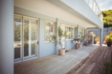 Düz dizayn geniş ahşap güverteyi korkuluk, sürgülü cam kapılar ve saksı bitkileriyle tasvir ediyor. Konut, açık hava, mimari, minimalizm, doğal, sükunet, dekor