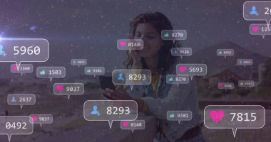 Akıllı telefon tutan, kot ceket giyen bir kadın çöl kanyonunda yüzen sosyal ikonlarla takılıyor. Dijital, açık hava, minimalist, teknoloji, iletişim, macera, doğa