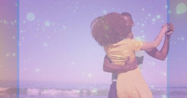 Pastel gökyüzünün altında kumlu kumsalda dans eden çift, yumuşak dalgalarla yuvarlanıyor. Aşk, eğlence, sükunet, uyum, açık hava, yaz, ışıltı