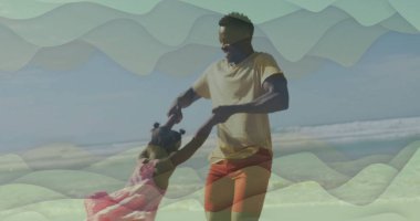 Dönen baba sarı tişört ve pembe elbiseli kız giyiyordu kumlu sahilde, güneş gözlüklü. Aile, deniz kenarı, eğlence, neşe, coşku, hareket, bağlantı