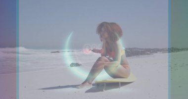 Turuncu bikinili bir kadın kumdaki sarı sörf tahtasından okyanusa bakıyor.% 0 dijital kaplama. Sahil, sahil, dinlenme, rahatlama, modern, canlı, macera.