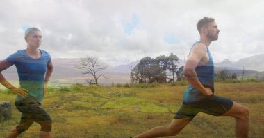 Askılı tişörtlü bir adam, şortlu bir adam, çayırda ileri atlama gösterisi yapıyor, desenli tozluklarla, kopya uzayı. Spor, açık hava, hareket, manzara, sağlık, egzersiz, canlılık