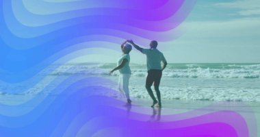 Kumsalda çıplak ayakla dans eden, okyanus dalgaları ve sığ sularla dans eden olgun bir çift. Romantik, boş zaman, dinginlik, bağlantı, açık hava, uyum, özgür ruhlu