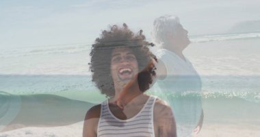 Kumsalda çizgili kolsuz tişörtlü gülen bir adam ve okyanus dalgalarının yanında uzanan yaşlı bir kadın. Neşe, huzur, açık hava, coşku, rahatlık, rahatlama, bağlantı