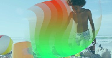 Turuncu kova ve plaj topuyla kıyı şeridinde kumdan kale inşa eden çömelmiş çocuk. Çocuk, açık hava eğlencesi, neşeli, enerjik, deniz kenarı, boş zaman, yaz